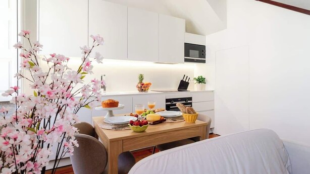 A modern kitchen with white cabinets, a microwave, and a dining area with a table set for breakfast.