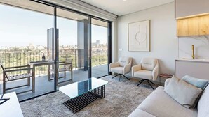 A modern living room with a glass balcony, a sofa, two armchairs, a coffee table, and a painting on the wall.