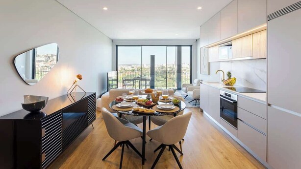 A modern kitchen with a dining area, large windows, and a view of the city.