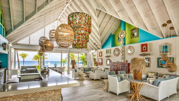A spacious, modern lounge area with a high ceiling, large windows overlooking the ocean, and a variety of seating options. - Villa with Private Pool and Sandy Lane Beach Club Access - Coral Gables (Sandy Lane)