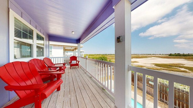 A covered porch with red Adirondack chairs and a view of the beach. - Private Heated Pool, Pet Friendly, Fire Pit (Port Aransas)