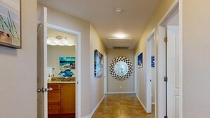 A hallway with a kitchen area on the left, a decorative mirror on the right, and a tiled floor. - Private Heated Pool, Pet Friendly, Fire Pit (Port Aransas)