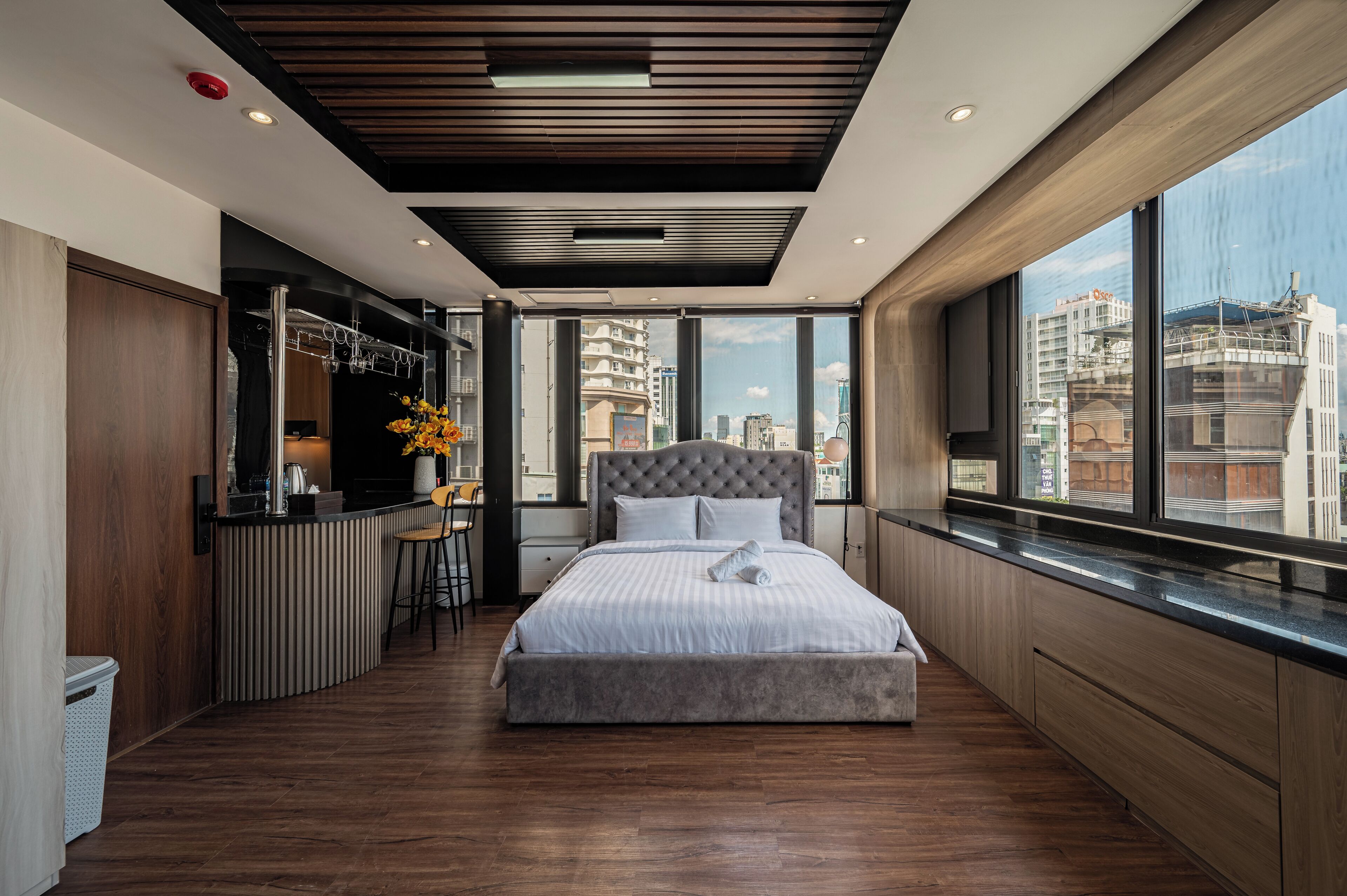 Ein modernes Hotelzimmer mit einem großen Bett, einer kleinen Küchenzeile und Blick auf die Stadt.