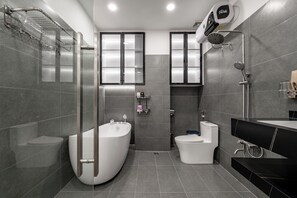 Ein modernes Badezimmer mit einer freistehenden Badewanne, Toilette, Duschbereich und Waschtisch mit Spiegel.