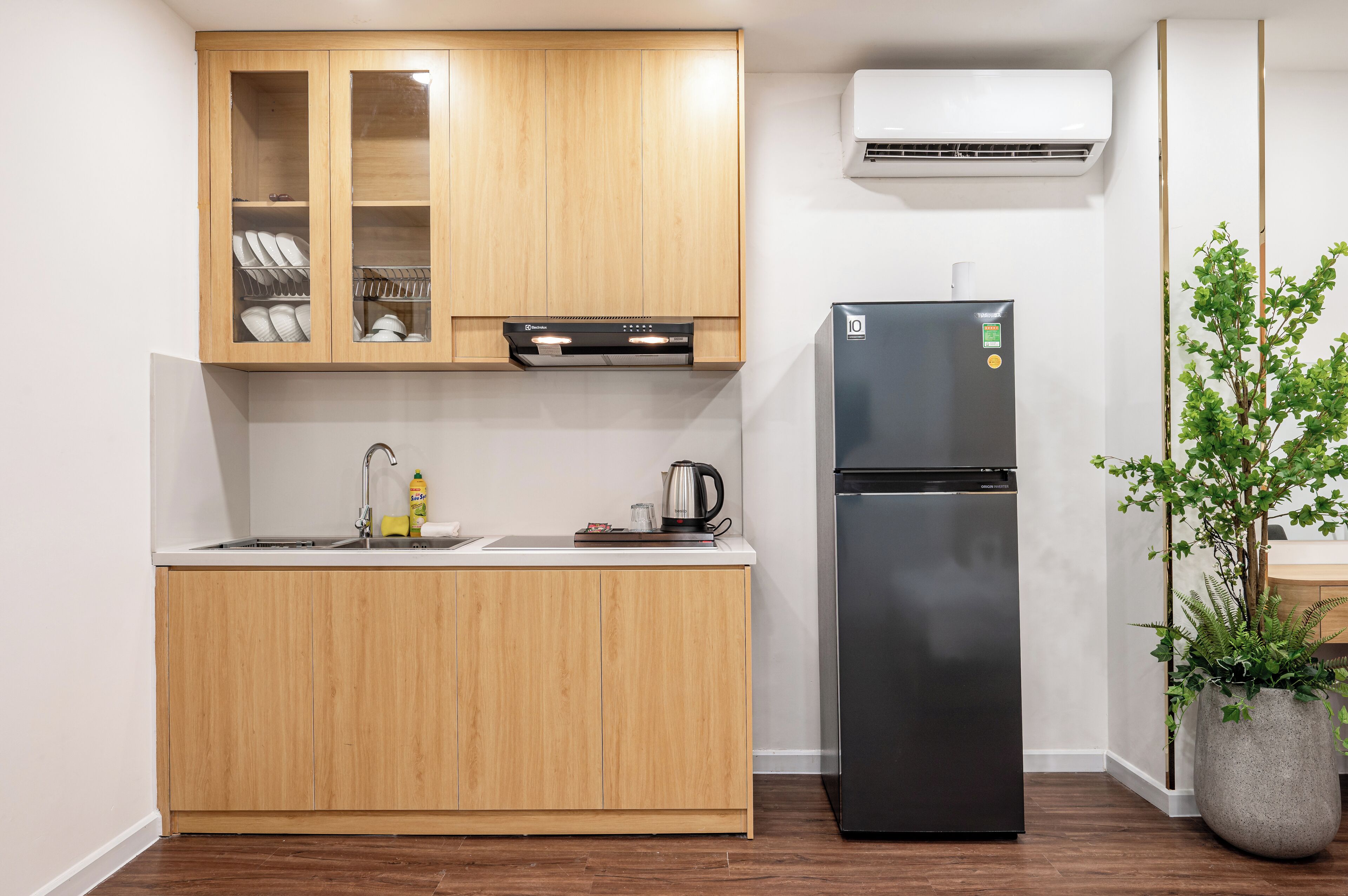 Una cocina moderna con armarios de madera, un refrigerador negro y una planta en maceta.