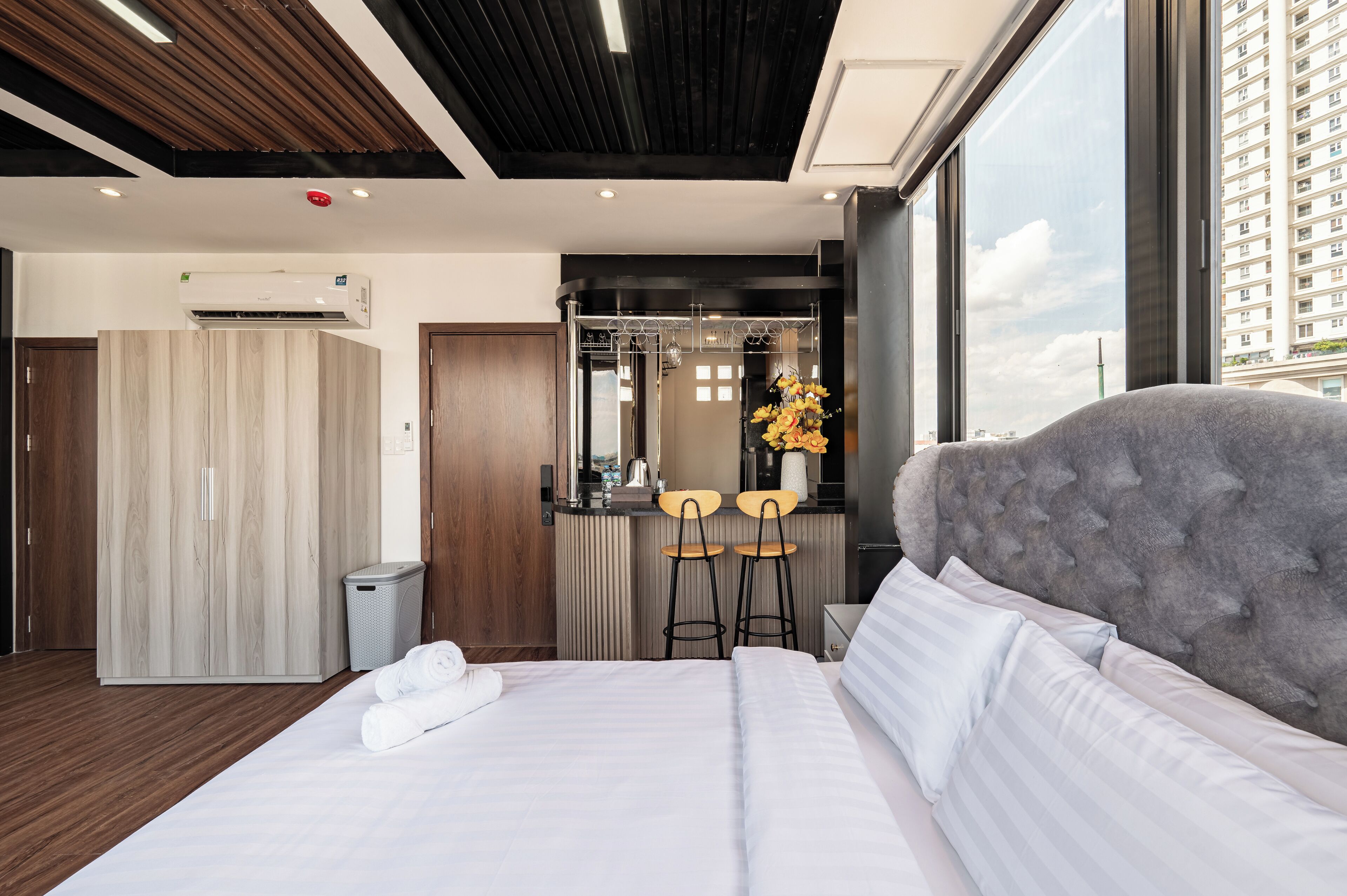 A modern hotel room with a large bed, a vanity with a mirror, and a view of the city.