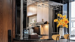 A modern kitchen with a built-in bar area, including a stainless steel sink, a wine cooler, and a vase with flowers.