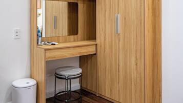 Ein kleines Zimmer mit einem Holzschrank, einem kleinen Hocker und einem Mülleimer.