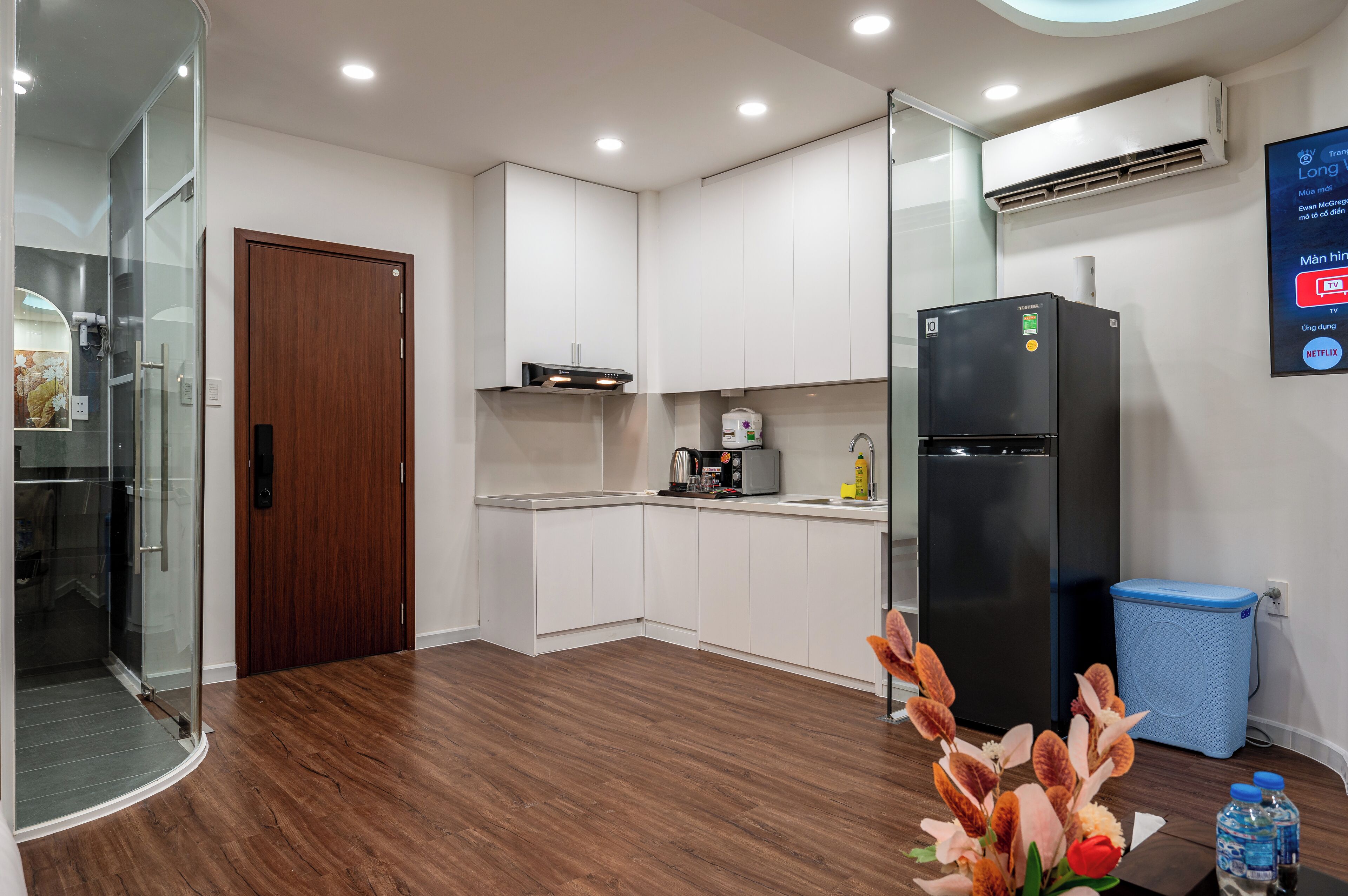Una cocina moderna con armarios blancos, un refrigerador negro y un cubo de basura azul.