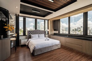 A modern bedroom with a large bed, a desk, and a view of the cityscape through large windows. - A Boi Apartment at District 3 (Ho Chi Minh City)