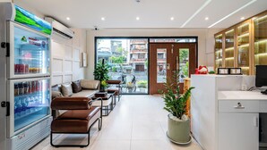 A modern hotel lobby with seating, a refrigerator, and a view of the street.