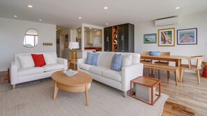 A modern living room with a white sofa, a round coffee table, and a dining area with a wooden table and chairs. - Ocean Front * 2 Panoramic Water View Decks * A/C (San Diego)