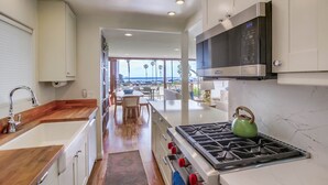 A modern kitchen with a stainless steel stove, white cabinets, and a view to the outside. - Ocean Front * 2 Panoramic Water View Decks * A/C (San Diego)