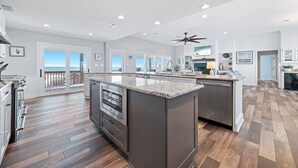 A modern kitchen with a large island, wooden flooring, and a view to the outside. - BEACHFRONT, BEAUTIFUL, FULLY RENOVATED HOUSE! (Gulf Shores)