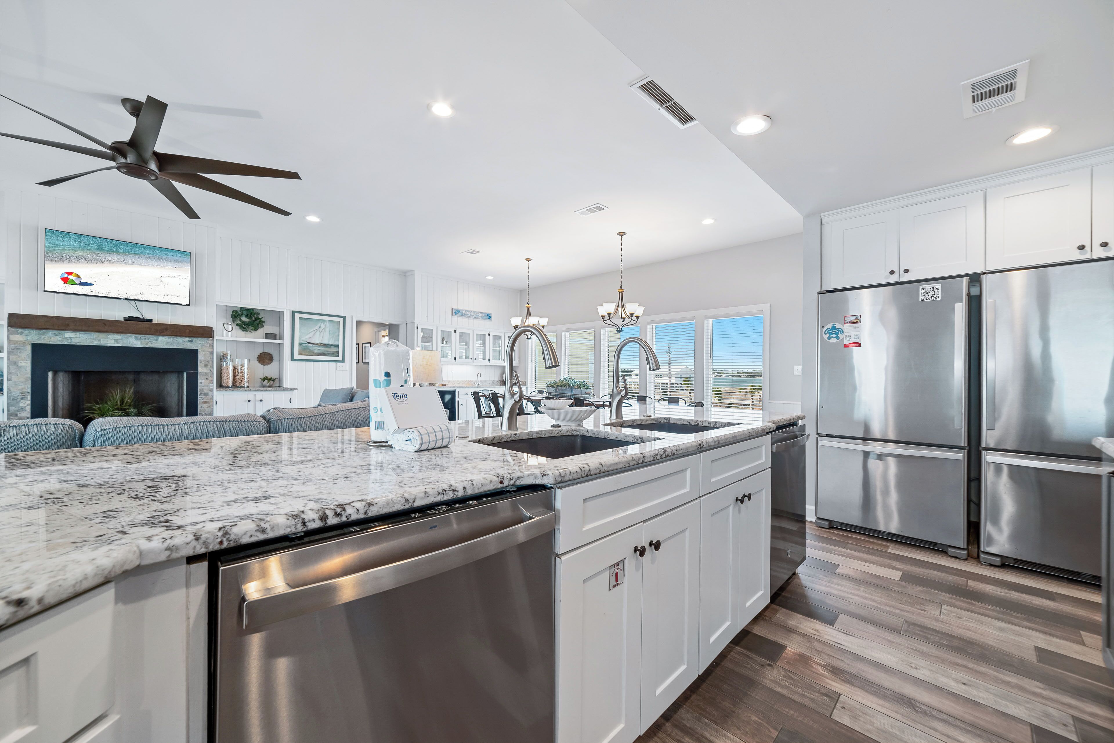 A modern kitchen with a large island, stainless steel appliances, and a ceiling fan.