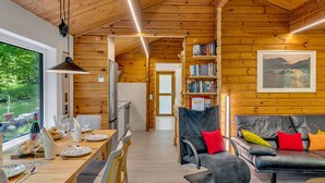 A cozy cabin interior with a wooden dining area, a sofa, and a bookshelf.