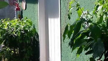 Una parete esterna verde con una porta bianca, un estintore e un cartello direzionale.