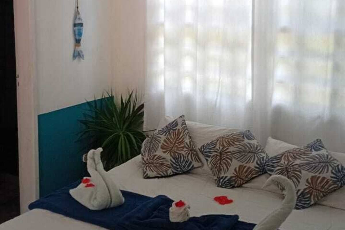 A bedroom with a bed, curtains, a hanging light, and a potted plant.