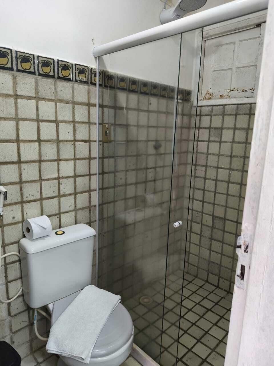 A bathroom with a toilet, a shower enclosure, and a tiled wall.