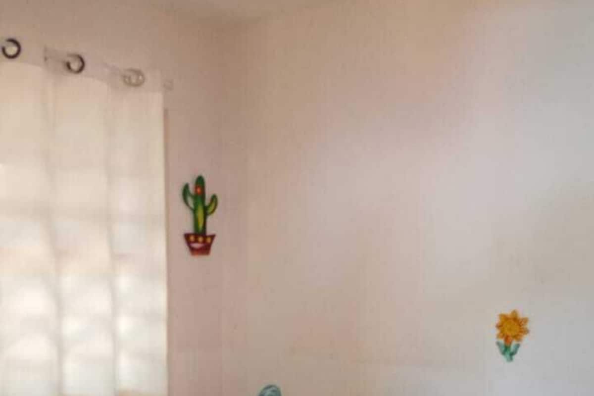 A bedroom with a bed, a potted plant, and a wall decoration.