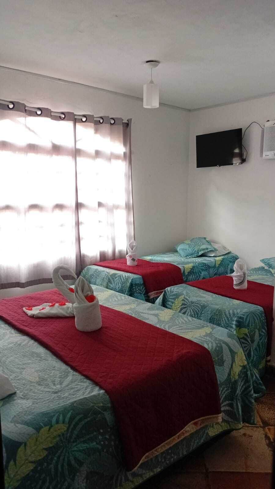 A hotel room with two beds, a TV, and a window with curtains.