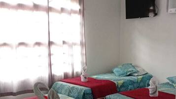 A hotel room with two beds, a TV, and a window with curtains.