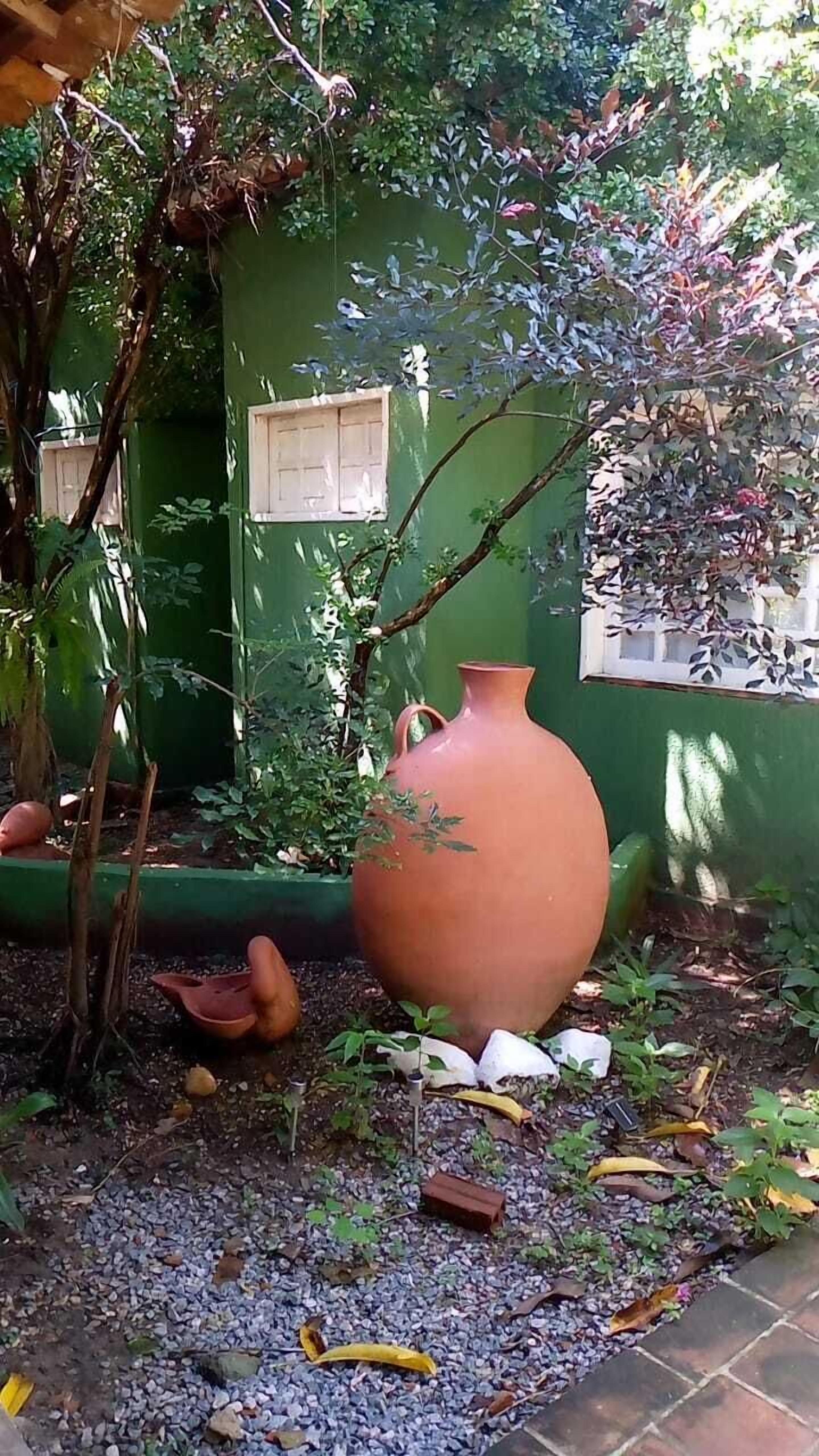 A garden with a large terracotta pot, a small clay pot, and a potted plant.