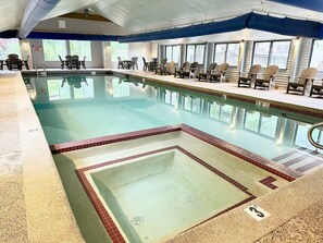 Ein Hallenbad mit Sprungbereich, Liegestühlen und einer überdachten Sitzgruppe.