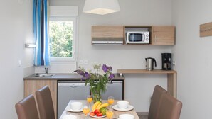Eine moderne Küche mit einem Esstisch für zwei Personen, einer Mikrowelle und einer Kaffeemaschine.