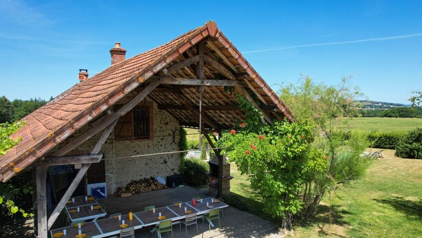Ein rustikales Steinhaus mit Ziegeldach und einer Holzdachterrasse.