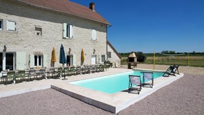Un bâtiment en pierre doté d’une piscine, d’un espace extérieur aménagé et de parasols.