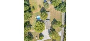 An aerial view of a residential area with a house, a swimming pool, and a driveway.