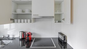A modern kitchen with white cabinets, a built-in oven, a coffee maker, a toaster, and a sink. - Blueground | Basel-Matthäus, view, nr Kunstmuseum (Basel)