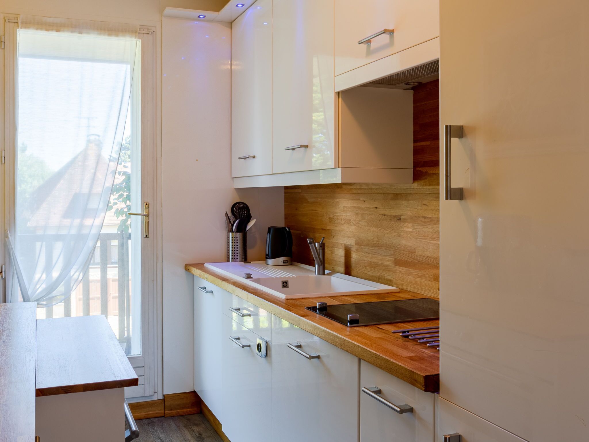 A compact kitchen with white cabinets, a wooden countertop, and a built-in stove.