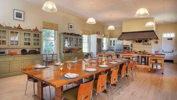 Une cuisine spacieuse avec une grande table à manger en bois, pouvant accueillir six personnes, entourée de chaises en bois. On y trouve de nombreux placards et un four encastré.