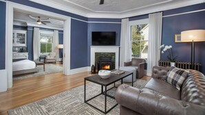 Una sala de estar con chimenea, televisor y sofá de cuero.