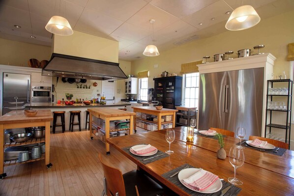 A modern kitchen with wooden countertops, stainless steel appliances, and a dining area set for four.