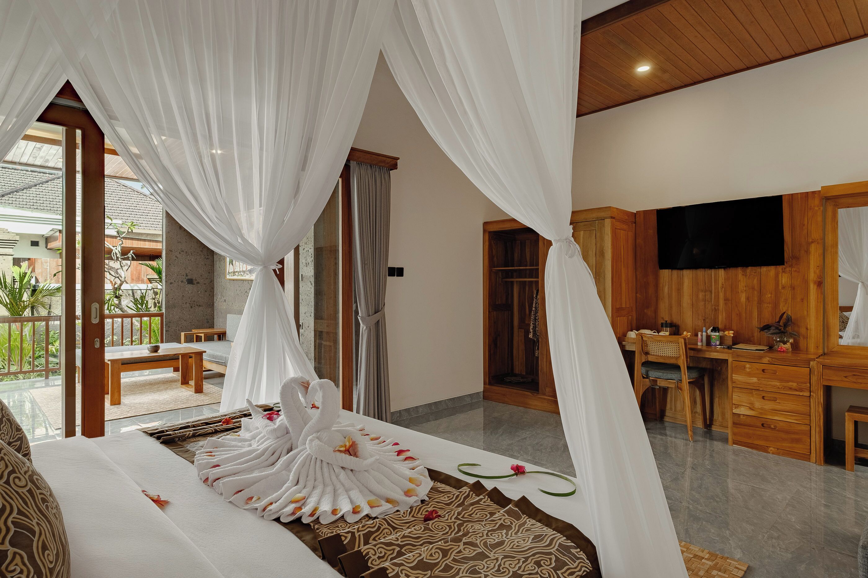 Een slaapkamer met een bed, een televisie, houten meubels en een balkon met uitzicht.