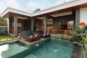Une maison moderne dotée d’une piscine, de chaises longues et d’une terrasse en bois.