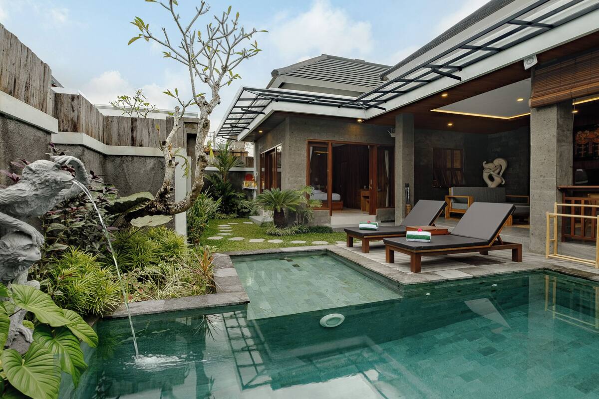 A modern outdoor pool area with lounge chairs and a small waterfall feature.