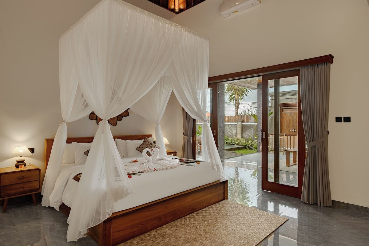A spacious bedroom with a large bed, a wooden headboard, and a canopy.