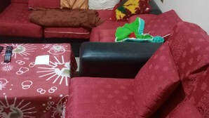 A living room with a red sofa, a black ottoman, and a patterned throw blanket. - Terrific 1-bedroom bed & breakfast in Cochabamba (Cochabamba)