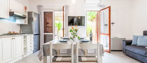A modern kitchen with white cabinets, a gas stove, and a dining area with a table set for two.