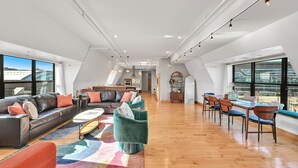 A spacious living area with a sofa, chairs, and a dining table. - Penthouse • Fiserv, Bars, Perks & Big City Views • Downtown Milwaukee (Milwaukee)