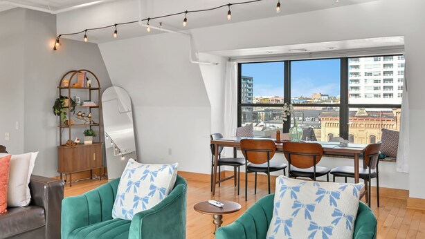 A modern living room with a dining area, large windows, and a city view. - Penthouse • Fiserv, Bars, Perks & Big City Views • Downtown Milwaukee (Milwaukee)