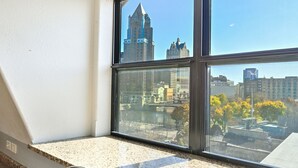 A kitchen with a granite countertop, stainless steel sink, and a window overlooking a cityscape. - Penthouse • Fiserv, Bars, Perks & Big City Views • Downtown Milwaukee (Milwaukee)