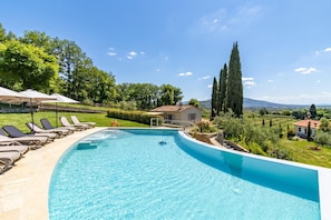 Une piscine avec des chaises longues et un petit bĂątiment en arriĂšre-plan.