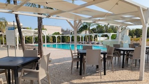 A poolside area with outdoor seating and a covered pavilion.