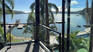 A balcony with a view of a lake, docked boats, and palm trees. - Peats Bite  (Berowra Waters)