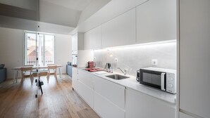 Een moderne keuken met witte kastjes, een ingebouwde magnetron en een raam met uitzicht op een stadsgezicht.